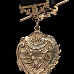 Detail of gold heart-shaped fob with running footballer holding football. Gold attachments and short chain.