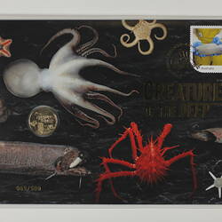 Multicoloured envelope depicting deep sea animals, with coin and stamp attached. In plastic sleeve.