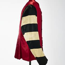 Profile of red riding jacket with red buttons. Black and white hoops on sleeves. Short stand up red collar.