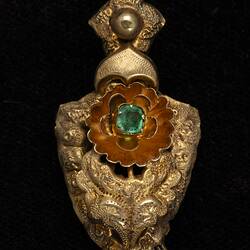 Gold and green paste pendant earring. Comprised of four connected sections with floral and leaf motifs. Gold fringe hangs from the bottom.