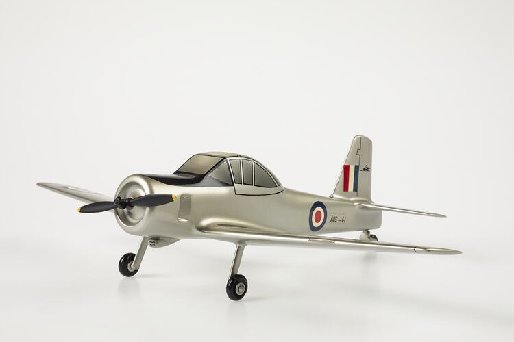 Model aeroplane, silver with black propeller and wheels. Red, white, blue roundels on body and flag on tail.