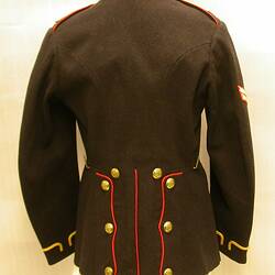 Black uniform jacket with red collar and trim, gold buttons and gold embroidery around sleeves, back view.