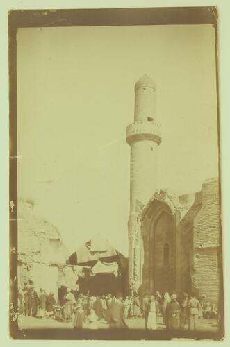 village scene with Minaret and people.