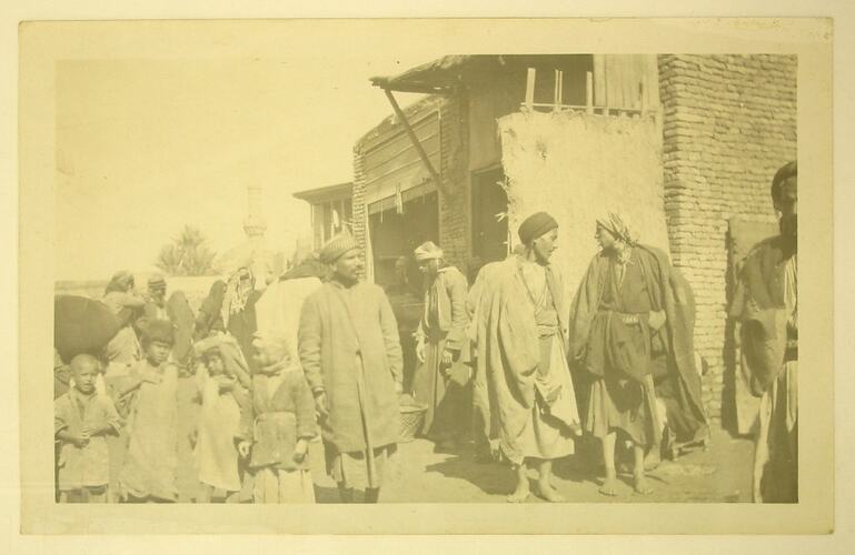 Group of Arab men and children standing outside a building.