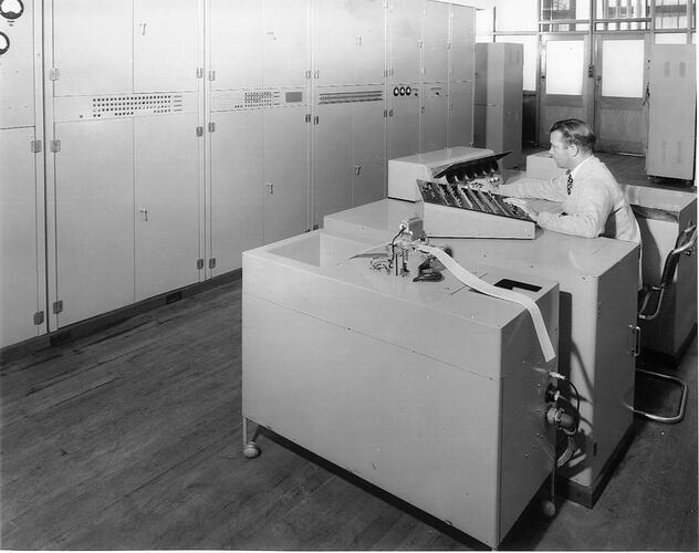 Man seated at machine with two control panels.