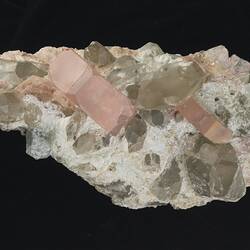 Grey-white rock with pink crystals on one surface.
