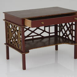 Dressing table in maroon with gold detail and open drawer.
