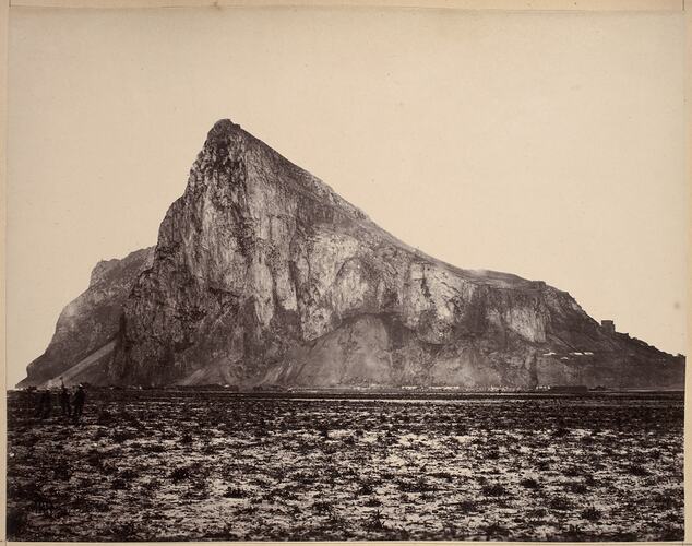 Pointy Rock of Gibralta with three men at left standing on the open plains.