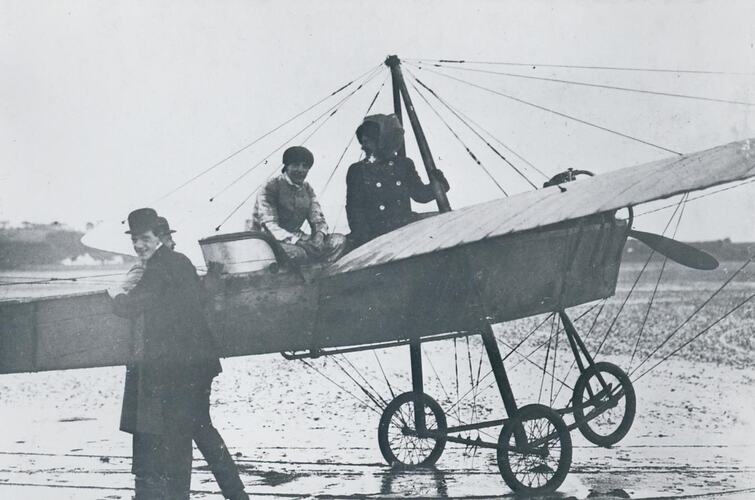 Two men in aircraft and two men standing next to it.