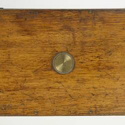 Rectangular wooden case with central inlay brass disc.