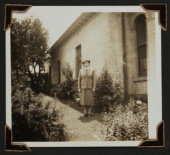 Woman in uniform standing in a yard next to a house.
