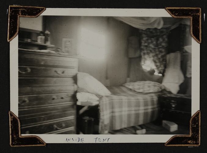 Room with chest of drawers, bed and trunk.