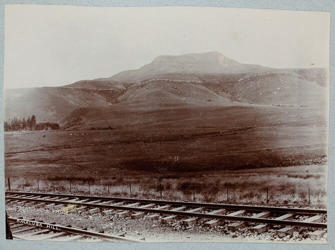 Mountain landscape with train tracks in foreground.