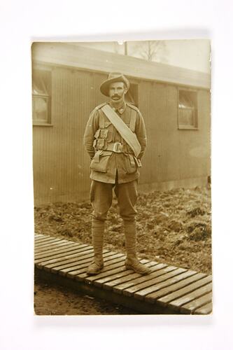 Front of postcard with solider on duckboard.