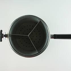 Inside circular pressure cooker showing three segment strainer.