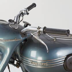 Blue metallic motor cycle. Handle bars and  tank with silver lettering detail, left side.