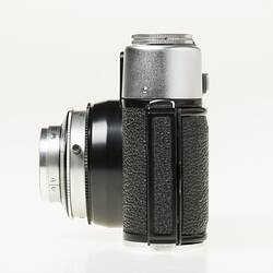 Black camera, metal trim, lens and top section. Left profile.