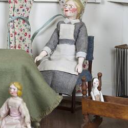 Doll's house interior room. Furnished nursery featuring costumed figures.