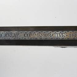 Detail of inscription on long narrow metal plate.