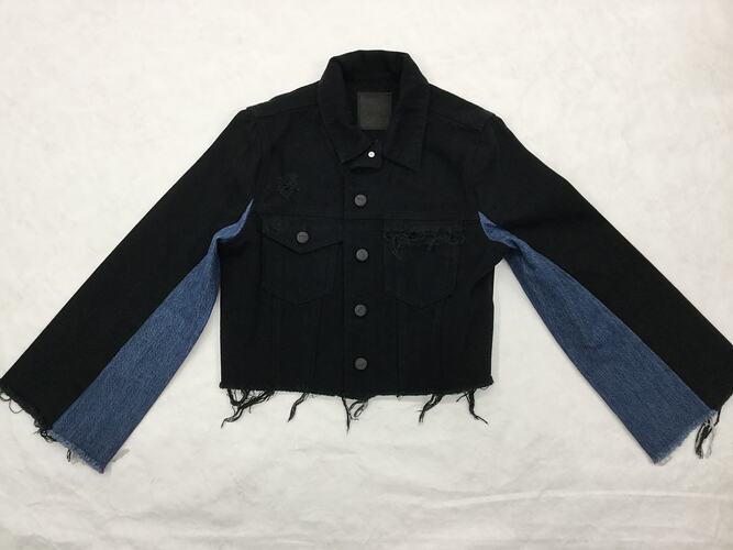 Short two-toned jacket made from blue and black denim.It has a collar, two pockets, long sleeves.
