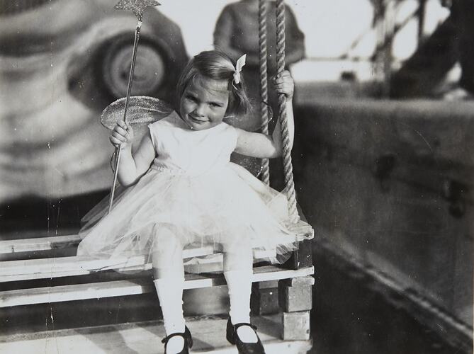 Girl seated wearing fairy costume and holding a wand.