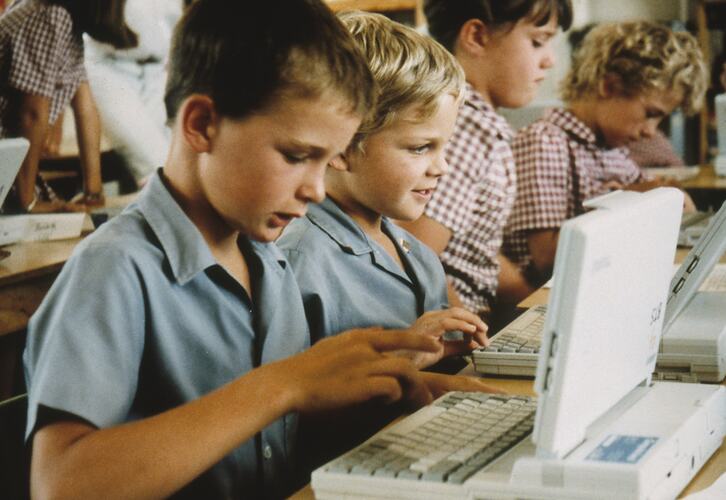 Students in school uniform with laptops.