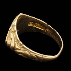 Profile of large gold ring with decorative band. Internal stamp visible.