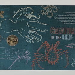 Blue/green card with drawings depicting deep sea animals, with coin attached.