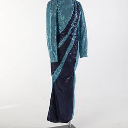 Aqua full-length sequin dress with navy swirls from left shoulder to right hip. Long sleeves, high neckline.