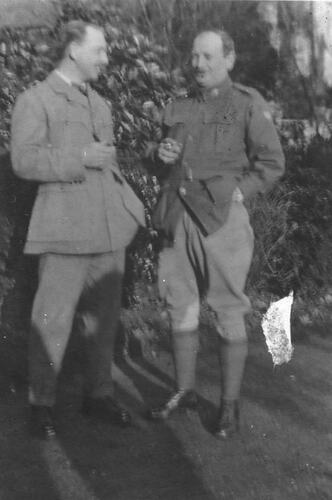 Two officers in military uniform, one smoking.
