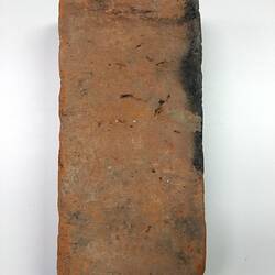 Red clay brick with soot blackened edge.