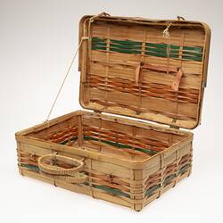 Cane basket, hinge lid. Orange and green stripe detail. Two handles at front. Open.