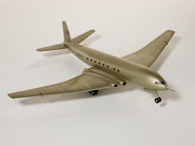 Silver model aeroplane, four wheels beneath each wing and two front wheels. British flag painted on tail.