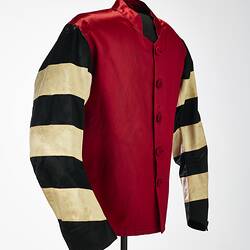 Red riding jacket with red buttons. Black and white hoops on sleeves. Short stand up red collar.