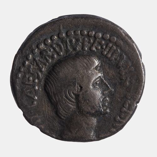 Rough round coin. Head of man facing right. Text above. Beaded arc above.