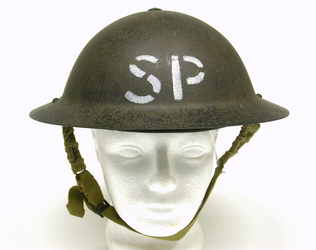 Metal helmet labelled SP on white foam head.