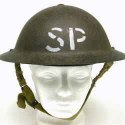 Metal helmet labelled SP on white foam head.