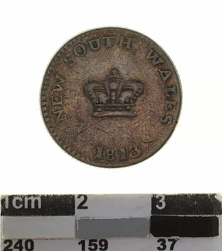 Darkened silver round coin with central crown, text around.