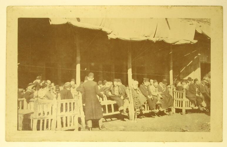 Arab men sitting under awning.