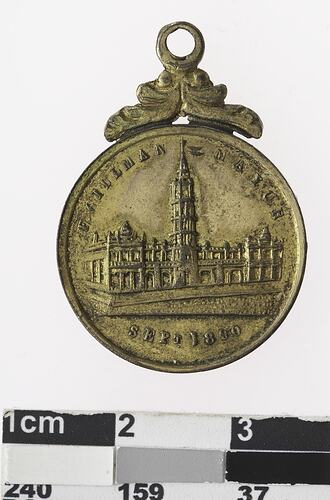 Round medal with building and text surrounding.