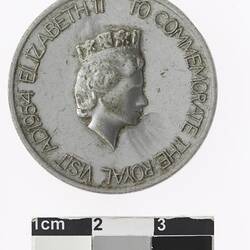 Round silver medal with profile of a crowned woman and text surrounding.