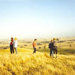 Five women standing in a paddock on top of a hill looking out over the landscape.