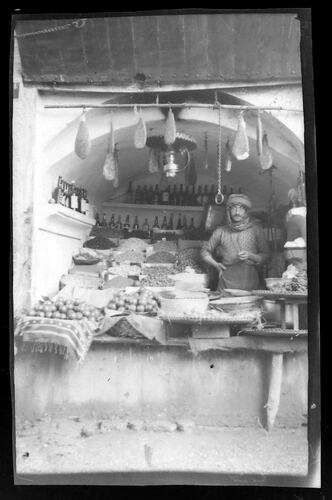 Woman standing in storefront with food items.