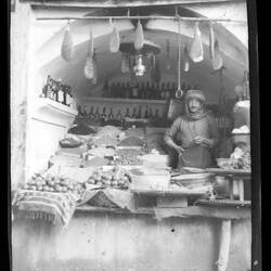 Woman standing in storefront with food items.