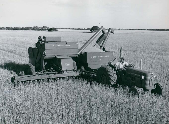 Man driving a tractor coupled to a harvester, with a trailed grain bin.