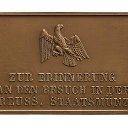 Eagle with partially outstretched wings. Inscription below.