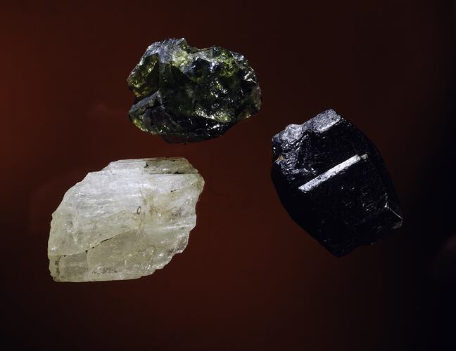 Three mineral specimens, one white, one green and one red.