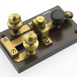 Ebonite base. Brass key with ebonite knob. Brass screw terminals. Top angled view.