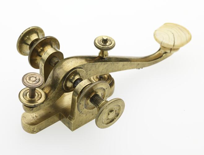 Curved brass pivoted lever, fitted with ivory knob. Three quarter view.