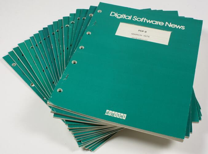 Pile of green magazines with white printed text.